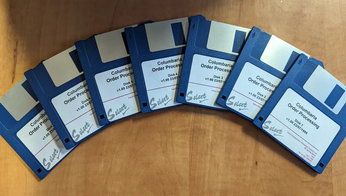 Seven floppy disks fanned out on a desk, labelled Columbaria Order Processing, version 1.00, dated 23 July 1999, with the old Select logo and a Hull phone number.
